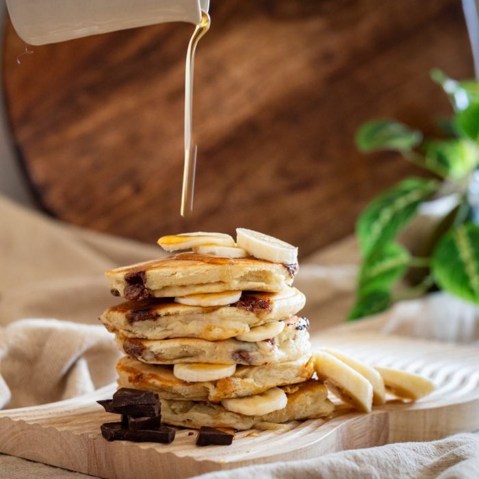 stack of banana packakes with maple syrup